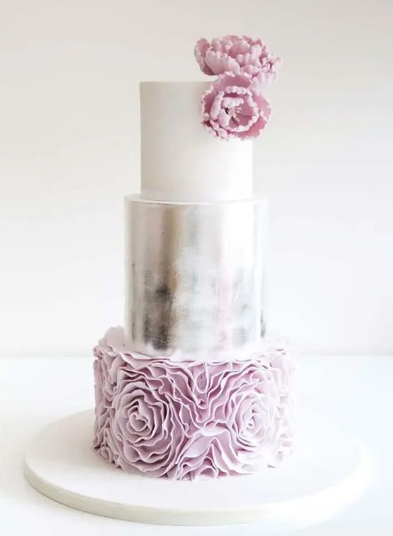 a refined and girlish wedding cake done with a white, silver and pale pink layers and some sugar blooms on top