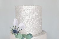 a silver glitter wedding cake decorated wiht greenery and a thistle is amazing for a modern glam celebration