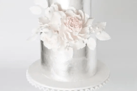 a silver wedding cake with white sugar blooms looks absolutely ethereal and extremely beautiful
