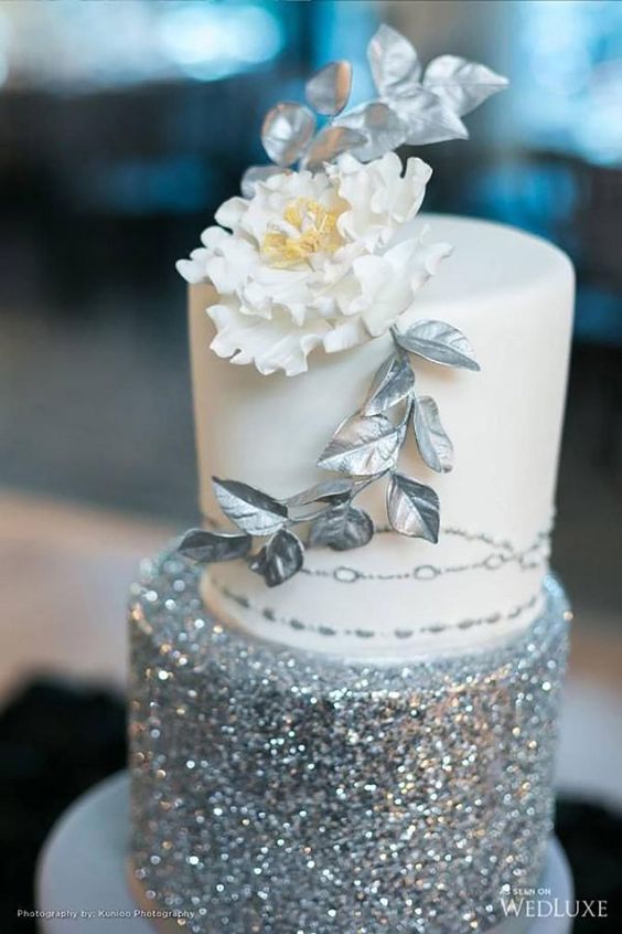 a white and silver glitter wedding cake topped with a sugar flower and silver leaves is amazing for a glam wedding