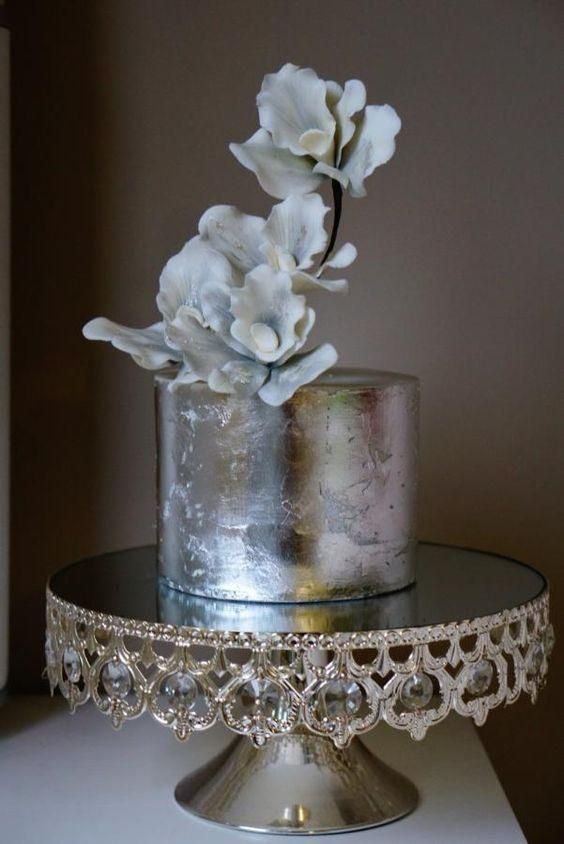 an elegant silver leaf wedding cake topped with sugar flowers looks very chic and very beautiful