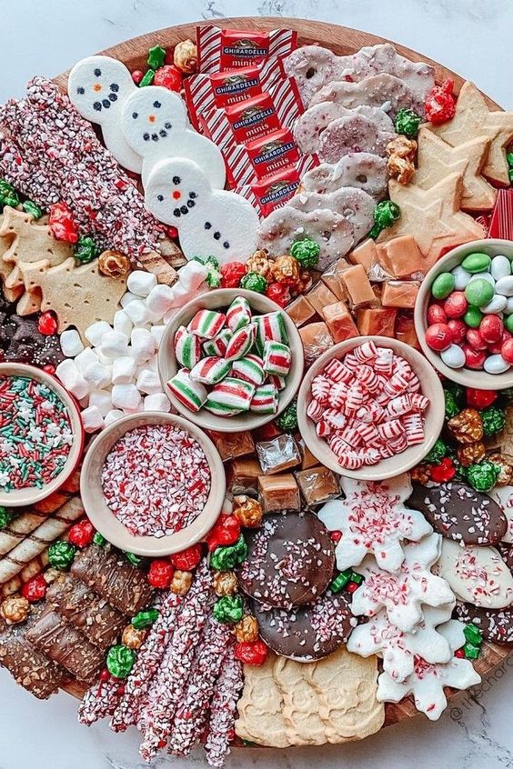a Christmas wedding dessert board with chocolate, cookies, cakes, mint candies, marshmallows, M&Ms, and lots of other tastes