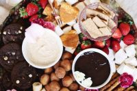 a beautiful dessert fondue platter with mini donuts, bananas, sweets, marshmallows, chocolate cookies, strawberries and various kinds of dip