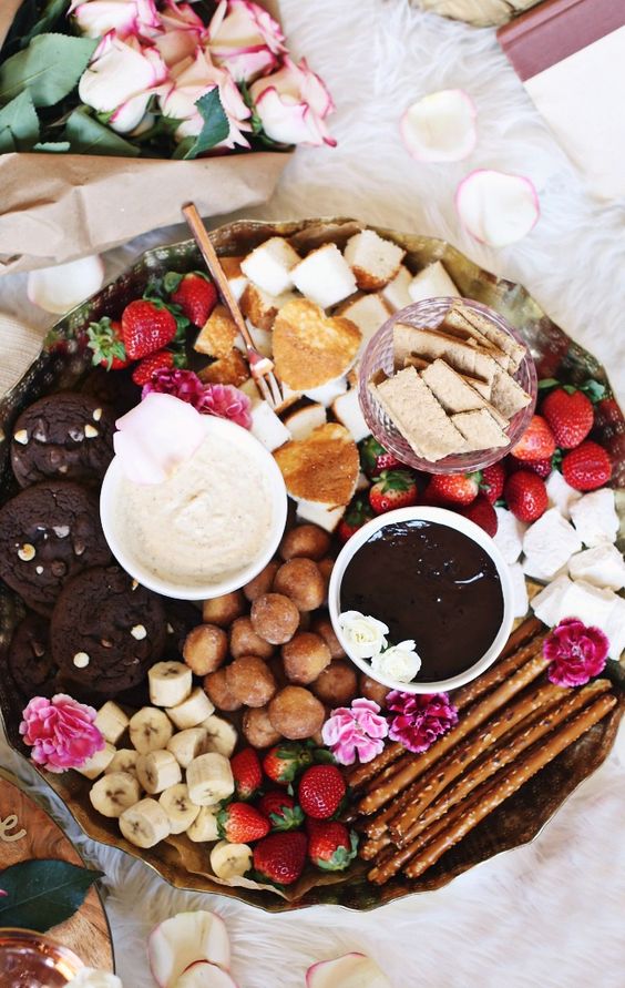 a beautiful dessert fondue platter with mini donuts, bananas, sweets, marshmallows, chocolate cookies, strawberries and various kinds of dip
