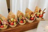 a charcuterie board with cones filled with olives, tomatoes, crackets and salami are amazing for a wedding, such individual cups are comfrotable for guests