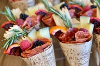 a clear acrylic stand with cones with charcuterie – cheese, berries, salami, fruit and herbs is a lovely idea to rock at your wedding
