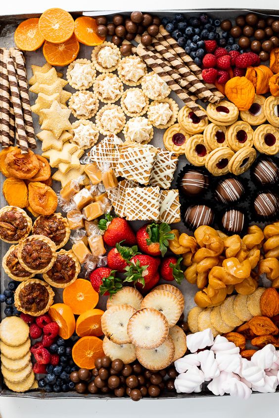 a fab wedding dessert board with marshmallows, cookies, dried fruit, tartlets, strawberries and blueberries, cakies and caramel is wow