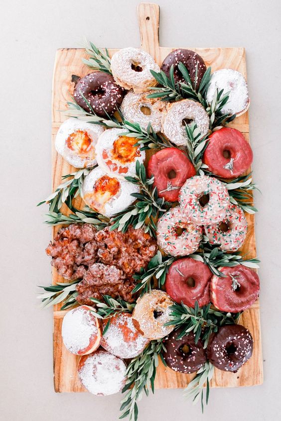 a fantastic donut grazing board with various types of glazed and non-glazed donuts and with greeneyr is a lovely idea for a relaxed wedding