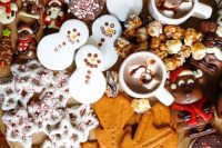 a hot chocolate grazing board with various glazed and non-glazed cookies, hot chocolate, marshmallows, popcorn and nuts
