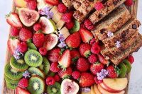 a lovely grazing board with figs, strawberries, kiwis, raspberries, bananas and a delicious cake and apples is amaizng for a wedding