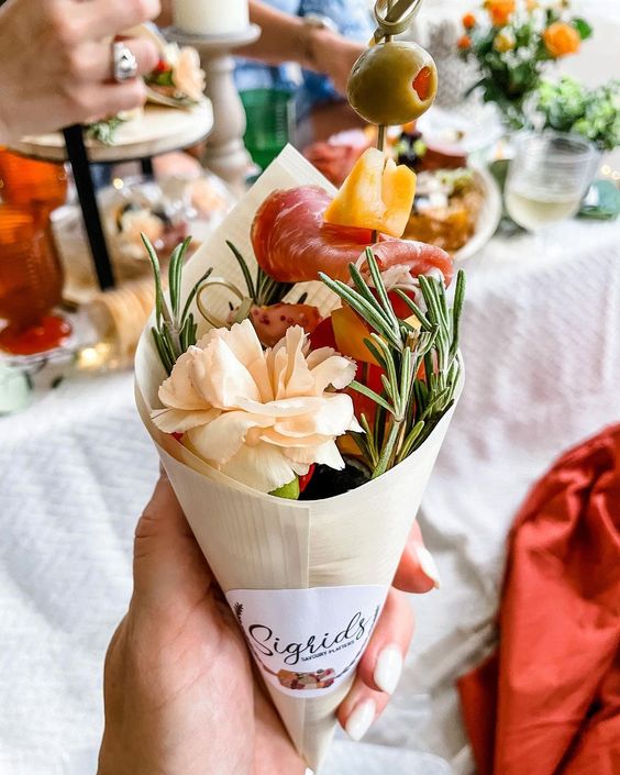 a romantic wedding charcuterie cone with herbs, salami, cheese, olives and a bloom is a lovely idea for a wedding
