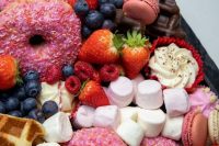 a slate-style platter with fresh berries, marshmallows, glazed donuts, cupcakes, macarons and meringues is a perfect idea for a party or a wedding