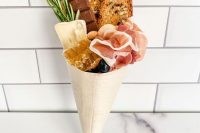 a yummy charcuterie cone with honey, ham, cheese, bread, chocolate and herbs plus olives is ideal for a wedding