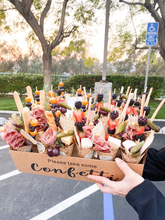 adorable charcuterie cones with cheese, pickled cucumbers, grapes, ham, salami, dried fruit and tomatoes for a wedding cocktail hour