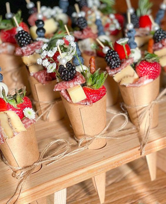 awesome charcuterie cones of cardboard, with cheese, salami, strawberries and blackberries, some blooms are amazing wedding appetizers