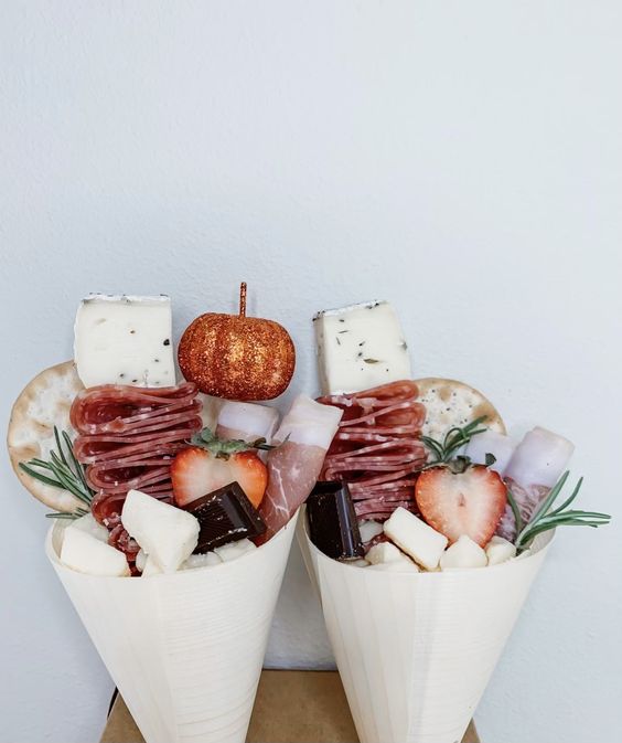 cool charcuterie cones of cheese, chocolate, strawberries, crackers, ham and prosciutto and a tiny glitter pumpkin for decor