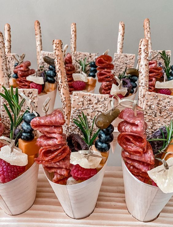 mouth-watering charcuterie cups with sesame cookies, salami and ham, cheese, berries, pickles and some herbs are gorgeous for a wedding