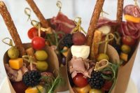 pretty and yummy-looking charcuterie cups with olives and tomatoes, cheese and ham, herbs and salted cookies are gorgeous