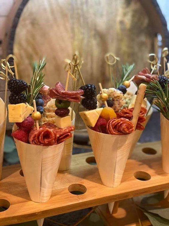yummy looking charcuterie cones with various types of cheese, salami, blackberries, herbs and berries are amazing for a summer wedding