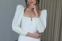 08 a beautiful and eye-catchy plain wedding dress with a square neckline, puff sleeves accented with buttons and a skirt with a slit that is also accented with buttons