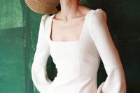 a beautiful plain fitting wedding dress with a square neckline and puff sleeves, a slit on the front, and wide brim hat and statement earrings finish off the look