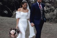 a beautiful lace mermaid wedding dress with an off the shoulder neckline and puff sleeves, a train and a long veil for a chic modern wedding