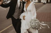 a beautiful modern wedding dress with a plunging neckline, puff sleeves and a long tiered skirt for a modern and romantic bride
