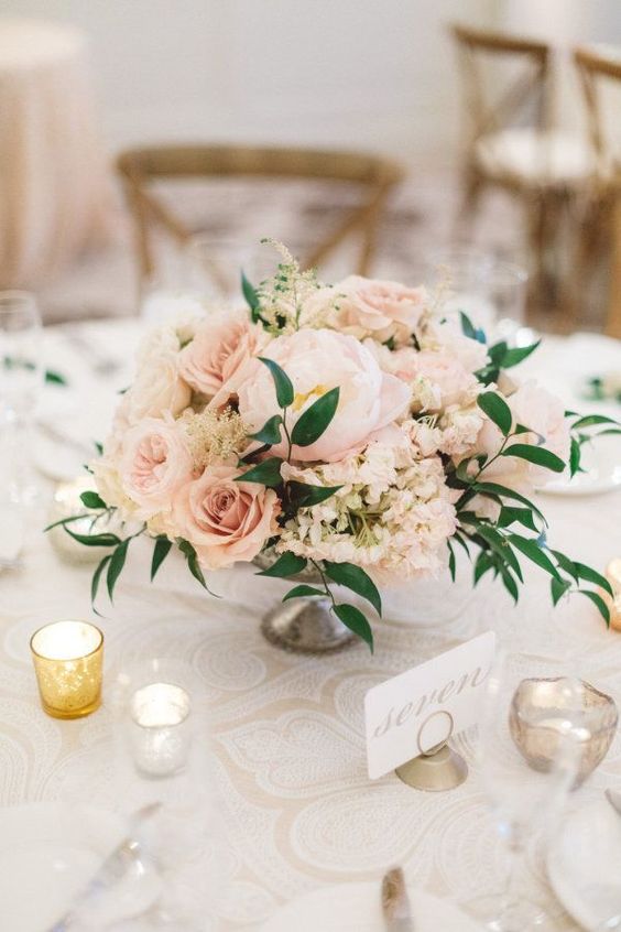 a blush wedding centerpiece of peonies, roses, peonies and greenery, candles around is a chic and tender idea for a spring or summer wedding
