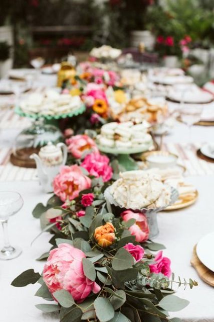 a bold floral wedding table runner with greenery, bold pink peonies, orange and pink roses is a lovely and colorful decoration