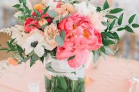 a bold wedding centerpiece of white, bold pink and orange blooms and greenery and candles around is a gorgeous idea for summer