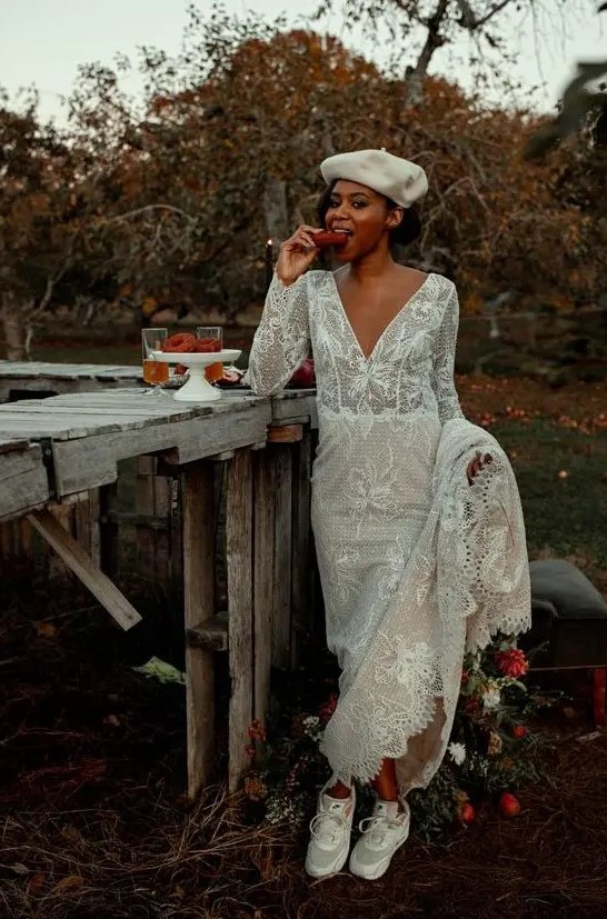 a chic boho lace A-line wedding dress with long sleeves, a V-neckline, grey trainers and a white beret for a wow look