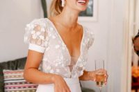 a chic modern bridal look with a floral applique bodice, a covered plunging neckline and puff sleeves plus a plain skirt