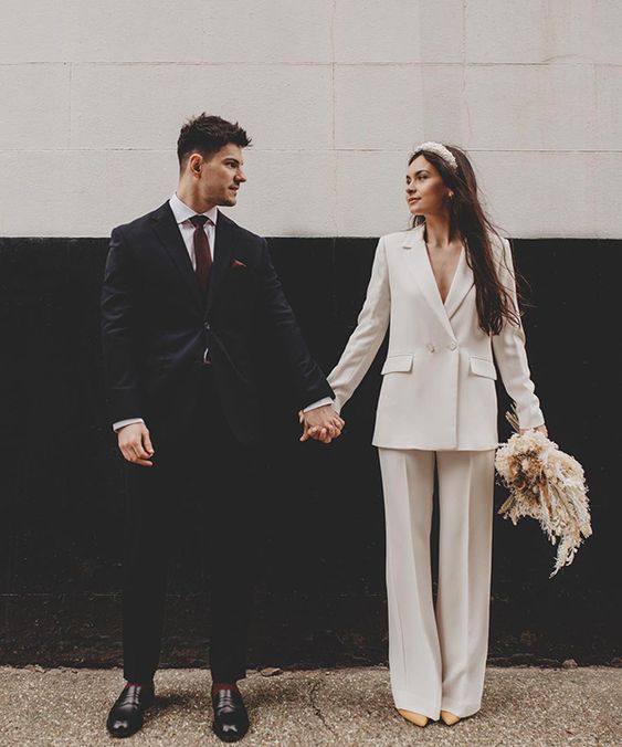 a chic white pantsuit with an oversized blazer, nude shoes and a large pearl headband for a modern bridal look