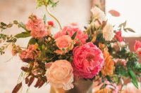 a colorful and dimensional wedding centerpiece of a black faceted vase, blush and pink peonies, blush roses, yellow ones and lots of various foliage