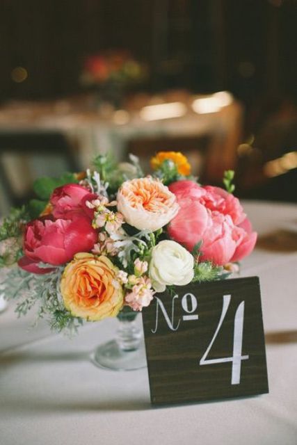 a colorful summer wedding centerpiece of bold pink peonies, blush and white blooms, yellow blooms and greenery is a beautiful idea for a wedding