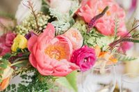 a colorful wedding centerpiece of pink peonies, blush peony roses, fuchsia ranunculus, lots of greenery and berries for summer