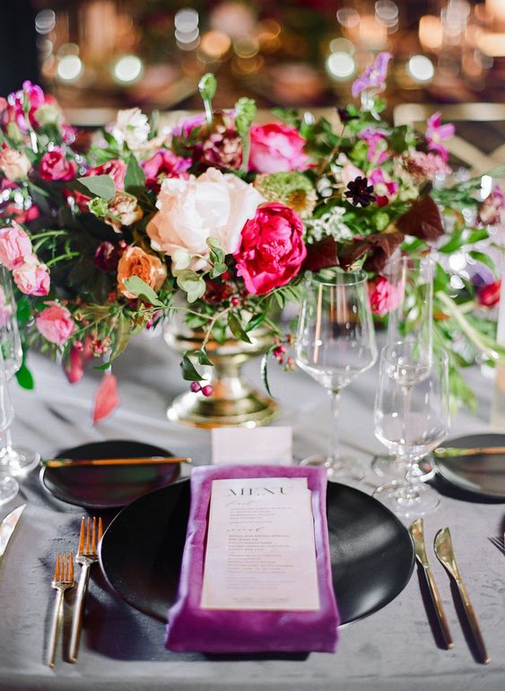 a colorful wedding centerpiece of pink roses, a pink and a white peonies, greenery and orange roses