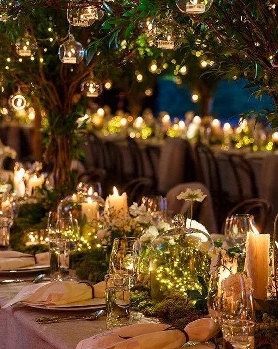 a fantastic enchanted forest wedding centerpiece of a tree with candle bubbles, cloches with lights and white blooms