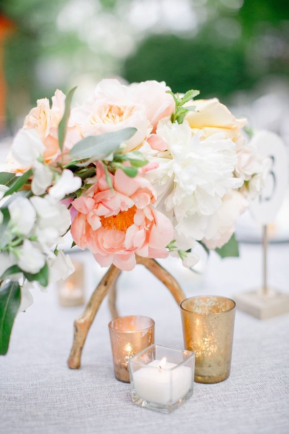 a lovely summer wedding centerpiece of white, light pink and yellow peonies, some greenery and a stand of gilded branches is amazing