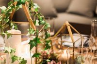 a lovely wedding centerpiece of house-shaped candle lanterns, greenery and some colorful succulents for an enchanted forest wedding