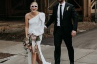 a modern plain one shoulder puff sleeve wedding dress with a slit and a train, white mules and pearl earrings