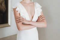 a modern plain sheath wedding dress with a plunging neckling, ruffle cap sleeves and statement metallic earrings