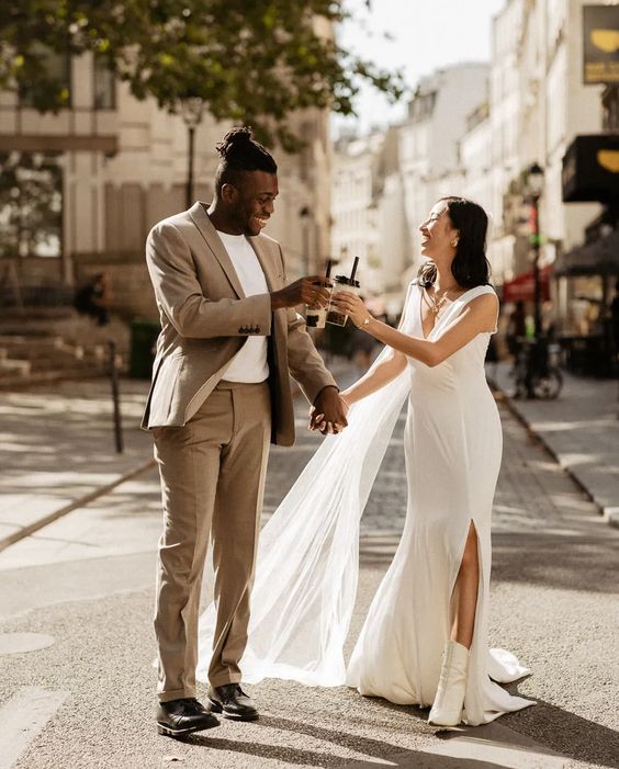 a modern thick strap wedding dress with a V-neckline and a slit, white boots and a long veil are a lovely combo for a modern wedding
