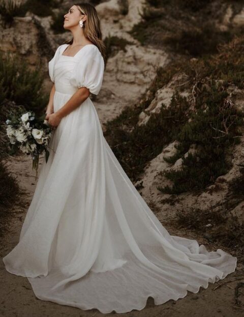 a modern wedding ballgown with a draped bodice and a square neckline, puff sleeves, a long veil and a long train for a romantic look