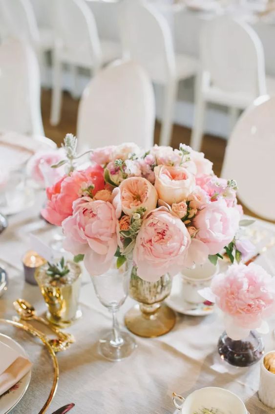 a refined and delicate summer wedding centerpiece of blush and pink peonies, peony roses and greenery for spring or summer