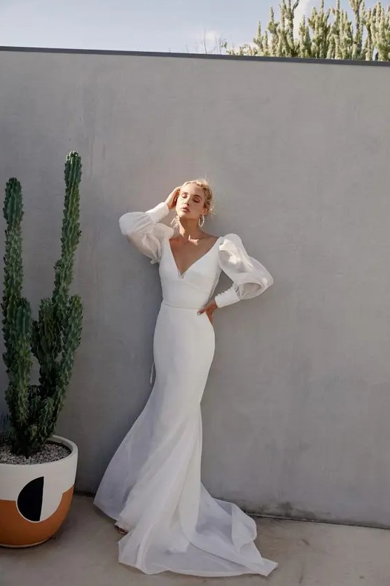 a sexy minimalist sheath wedding dress with a deep neckline, sheer puff sleeves and a train for a modern bride