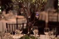 a simple and lovely enchanted forest wedding centerpiece of a tree with little lights and candle lanterns is amazing and can be DIYed