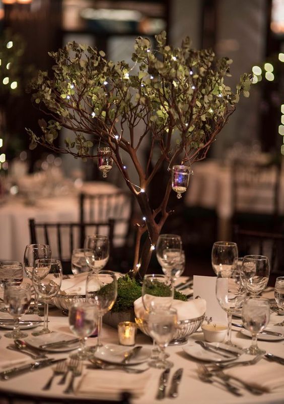 a simple and lovely enchanted forest wedding centerpiece of a tree with little lights and candle lanterns is amazing and can be DIYed