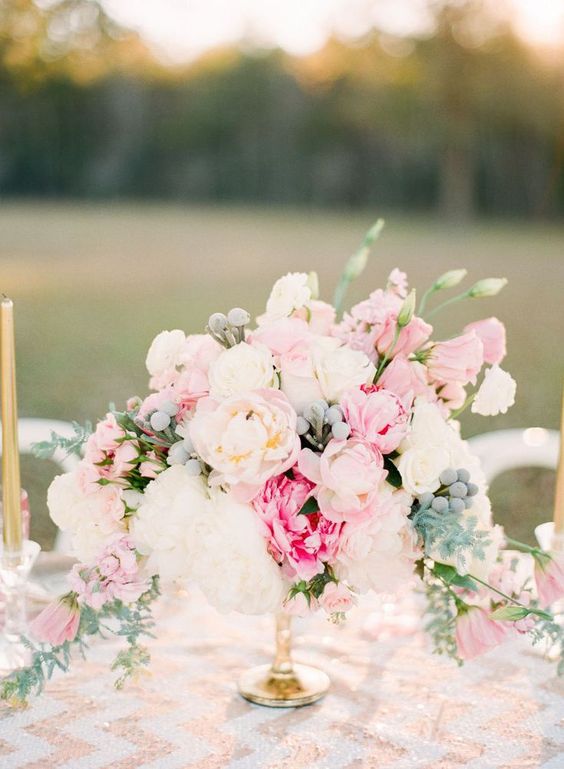 a sweet and lush wedding centerpiece of white and pink eponies, pale greenery and berries and ranunculus is amazing for summer