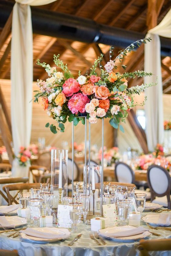 a tall and bright wedding centerpiece of blush and orange roses, pink peonies and lots of greenery is a fantastic and bright idea for a colorful wedding